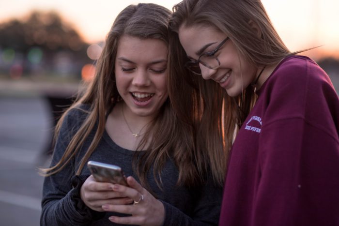 WhatsApp weiterleiten: Zwei junge Mädchen mit Smartphone haben Spaß. Foto: unsplash.com/Blake Barlow