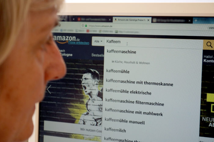 Auf Schnäppchenjagd? Frau blickt auf PC-Bildschirm, der die Startseite von Amazon mit Suche nach Kaffeemaschine zeigt. Bild: Verbraucherzentrale NRW