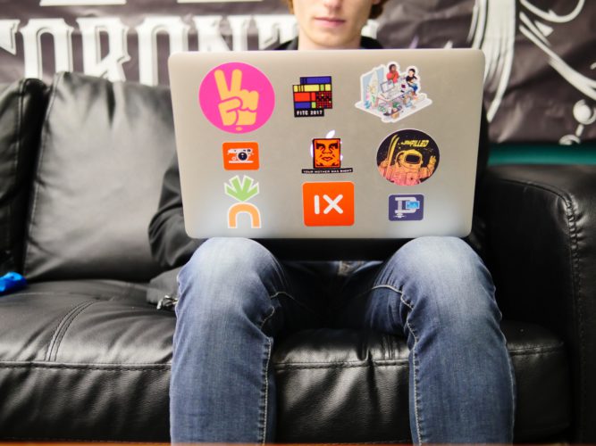 Zu sehen ist ein Mann, der mit einem Laptop auf dem Schoß auf dem Sofa sitzt. Er will einen Videocall starten. Bild: Unsplash/imgix