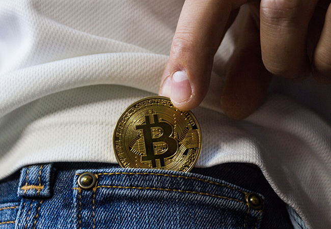 Bitcoin-Betrug: Jemand zieht einer Person einen Bitcoin aus der Hosentasche. Bild: Pexels/Worldspectrum
