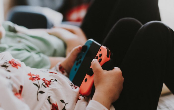 Zwei Personen liegen im Bett, eine von Ihnen hält einen Nintendo-Switch-Controller. In der Corona-Zeit sind digitale Spiele beliebt. Bild: Unsplash/Kelly Sikkema