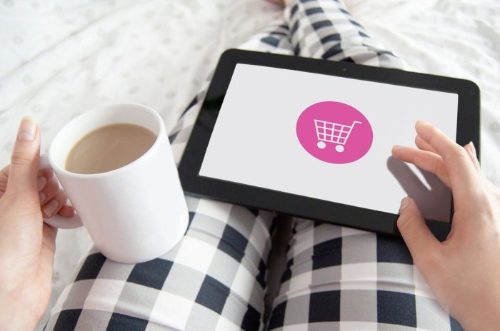 Online-Käufe: Tablet mit Einkaufswagen-Symbol liegt auf den Beinen einer Person mit Kaffee in der Hand. Bild: Pixabay