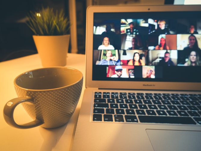 Zoom-Limit: Laptop mit vielen Teilnehmern einer Videokonferenz, Kaffeetasse daneben. Bild: Unsplash/Compare