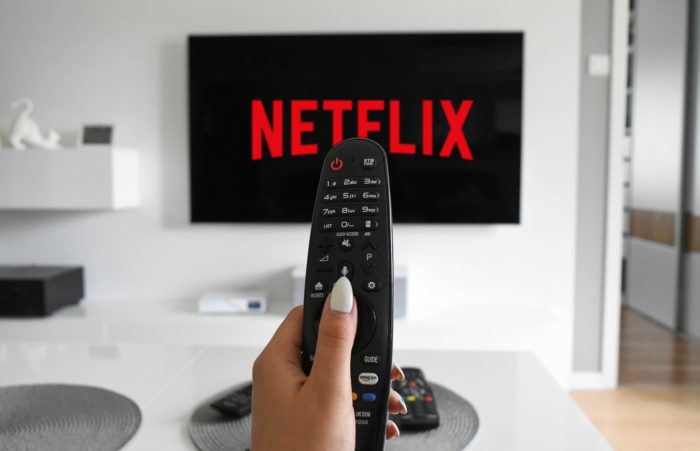 Netflix 2021: Fernseher mit Netflix Startbildschirm und Hand, die Fernbedienung hält. Bild: Pixabay