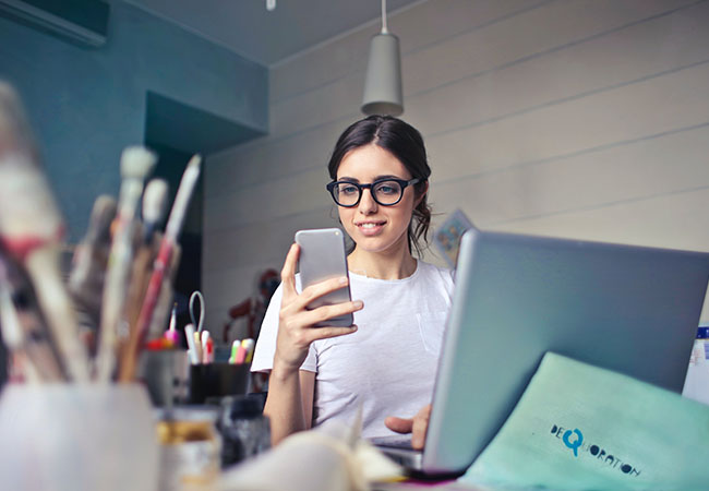 Signal-Messenger-Desktop: Frau sitzt am Computer und blickt nebenbei auf ihr Handy. Bild: Pexels/Andrea Piacquadio