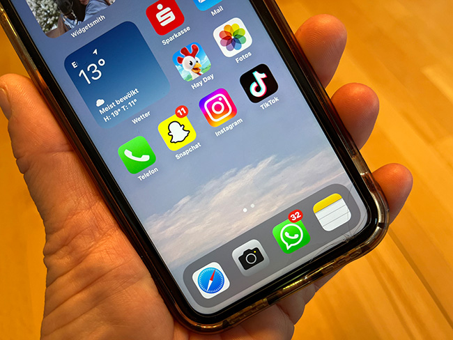 WhatsApp-Urlaubsmodus: Hand hält Handy. Display mit Apps und zahlreichen neuen WhatsApp-Nachrichten. Bild: ©PC-SPEZIALIST