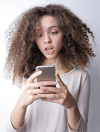 Blue WhatsApp: Junge Frau blickt erschrocken auf ihr Handy. Bild: Pexels/Andrea Piacquadio