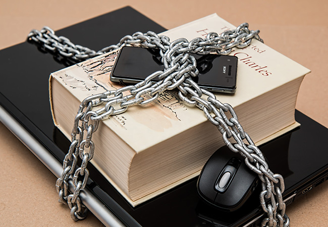 Laptop, Buch, Handy und Maus mit Ketten vor Zugriffen von außen geschützt. Bild: Pexels/Pixabay