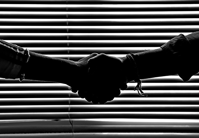 Schwarz-weiß-Bild: Zwei Personen geben sich die Hand. Bild: Pexels/Savvas Stavrinos