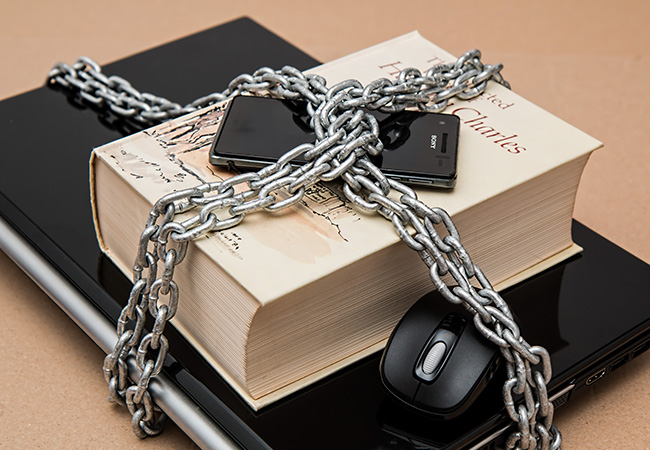 Lagebericht zur IT-Sicherheit: Laptop, Buch, Handy und Maus mit Ketten verschlossen. Bild: Pexels/Pixabay