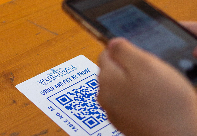 QR-Code auslesen: Person hält Handy in der Hand und scannt einen QR-Code. Bild: Unsplash/Albert Hu