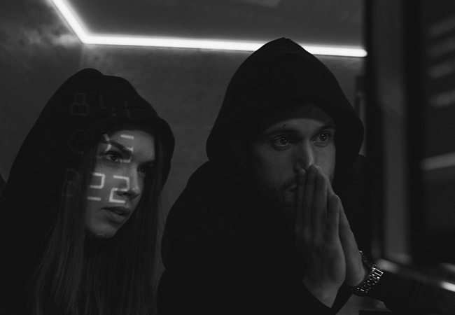 Roaming Mantis: Zwei dunkel gekleidete Personen in einem dunklen Raum starren auf einen Bildschirm. Bild: Pexels/Tima Miroshnichenko