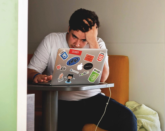 DEX: Mann mit ernstem Blick und Hand in den Haaren am Laptop. Bild: Pexels/Tim Gouw