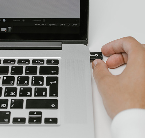 IT-Sicherheitsgesetz 2.0: Aufgeklapptes Laptop, Hand steckt verschlüsselten USB-Stick ein. Bild: Pexels/Cottonbro