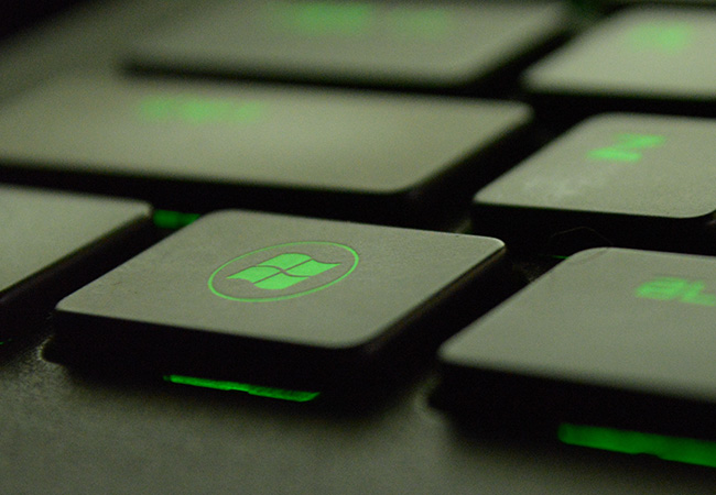 Windows-Patchday: Schwarze Tastatur grün beleuchtet, Windows-Taste. Bild: Pexels/Max Deroin