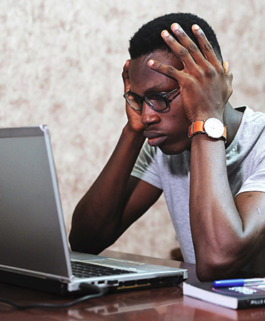 CCleaner Pro: dunkelhäutiger Mann sitzt verzweifelt vor Laptop, Hände am Kopf. Bild: Pexels/Oladimeji Ajegbile