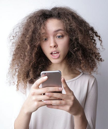 Smishing | Phishing | Junge Frau schaut erschrocken auf ihr Smartphone. Bild: Pexels/Andrea Piacquadio