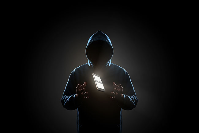 Smishing: Weißes Smartphone mit Text "HACKER" auf dem Bildschirm schwebt über der Hand des Hackers in dunklem Hintergrund. Bild: ©poravute/stock.adobe.com