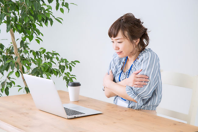 Home-Office-Pflicht: Frau am Schreibtisch mit Laptop, hält sich selbst im Arm, friert. Bild: ©buritora/stock.adobe.com