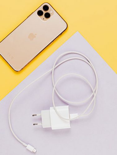 USB Type C: Ansicht von oben auf iPhone und Ladekabel auf gelb-weiße Untergrund. Bild: Pexels/Karolina Grabowska