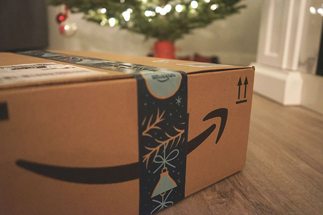 Amazon Marketplace: Amazon-Paket auf Fußboden, Weihnachtsbaum im Hintergrund. Bild: Unsplash/©Wicked Monday