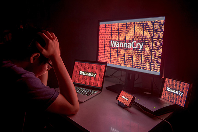 Erpressertrojaner: Junger frustrierter Mann nach Hackerangriff mit WannaCry auf Desktop-Bildschirm, Notebook und Smartphone. Bild: stock.adobe.com/©zephyr_p
