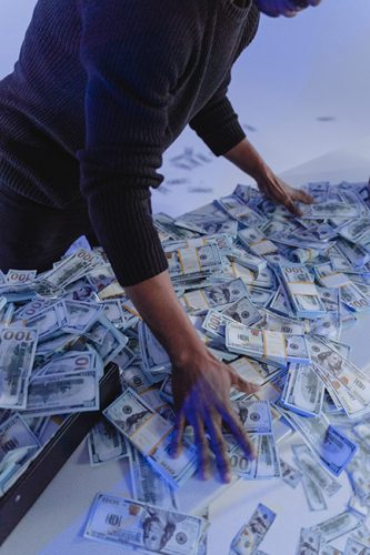 Erpressertrojaner; Jemand wühlt in einem Haufen Geldscheine, die auf einem Tisch liegen. Bild: Pexels/@tima-miroshnichenko