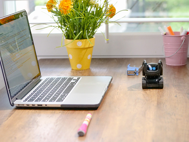 ChatGPT: Laptop auf Schreibtisch mit Blumen, davor ein kleiner Roboter als Sinnbild für die neue KI. Bild: Pexels/@kindelmedia