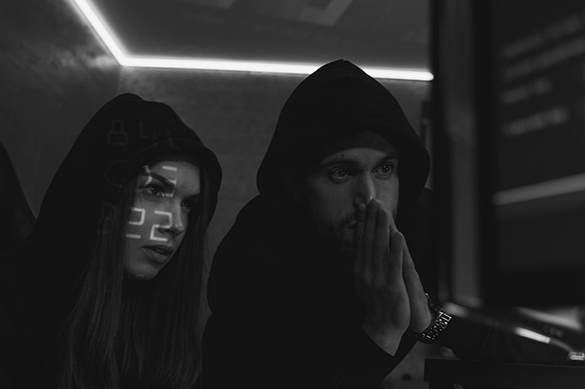 Ethical Hacking. Zwei Personen mit Kapuzen im Dunkeln. Bild: Pexels/@tima-miroshnichenko
