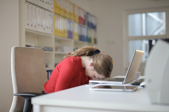 Vier-Tage-Woche: Frau, die ermattet mit dem Kopf auf dem aufgeklappten Laptop liegt. Bild: Pexels/@olly