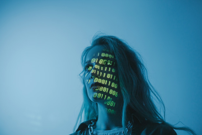 EU-AI-Act: Frau mit binären Zeichen blickt ernst in die Ferne. Bild: Pexels/cottonbro studio (https://www.pexels.com/de-de/foto/frau-ernst-verschlusselung-weiblich-5473955/)