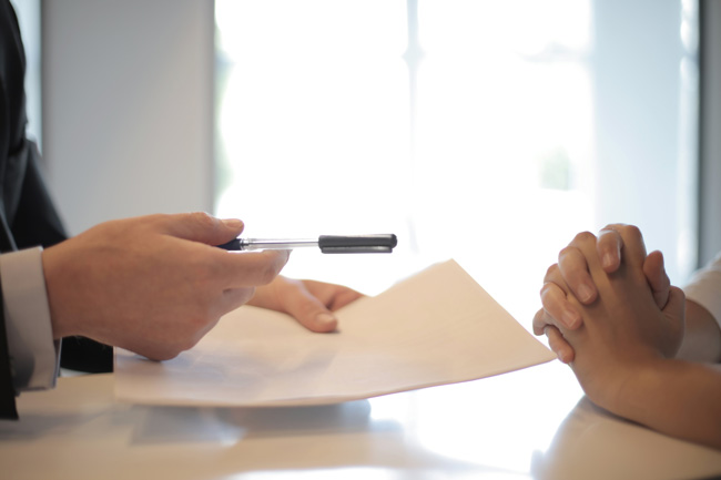 Papier und Stift wird zur Vertragsunterzeichnung gereicht. Bild: Pexels/Andrea Piacquadio (https://www.pexels.com/de-de/foto/ernte-geschaftsmann-der-vertrag-zur-frau-gibt-um-zu-unterzeichnen-3760067/)