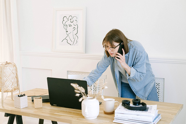 IP-Adresse: Frau mit Handy steht gebeugt vorm Laptop. Bild: Pexels/Ivan Samkov (https://www.pexels.com/de-de/foto/frau-becher-smartphone-schreibtisch-4240498/)