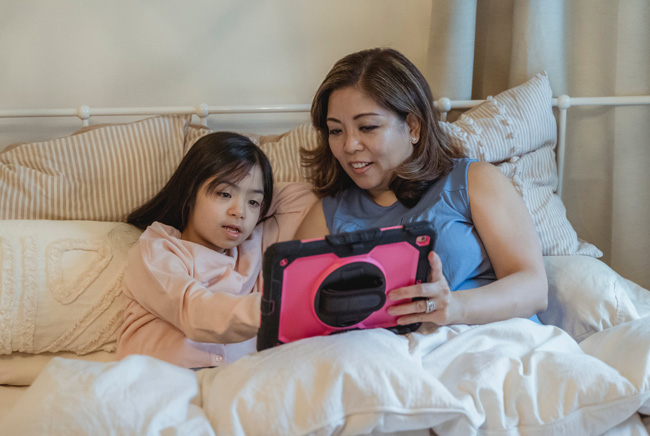 Mutter und Tochter gemeinsam an einem Tablet für Kinder. Bild: Pexels/Nicola Barts (https://www.pexels.com/de-de/foto/frau-madchen-bett-tablet-7943205/)