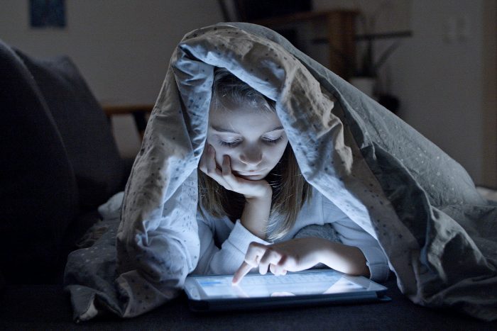 Tablet für Kinder: Mädchen im Dunkeln unter der Bettdecke am Tablet Bild: Pexels/Kampus Production (https://www.pexels.com/de-de/foto/madchen-tablet-kind-decke-7414096/)