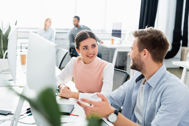 Cloud-Speicher: Lächelnde Geschäftsleute unterhalten sich in der Nähe von Computern und Notebooks auf dem Tisch im Büro. Bild: stock.adobe.com/LIGHTFIELD STUDIOS (https://stock.adobe.com/de/images/smiling-businesspeople-talking-near-computers-and-notebook-on-table-in-office/390655496?asset_id=390655496)