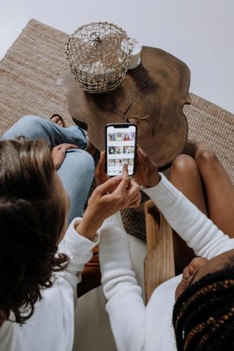 iPhone-Screenshot: Zwei Personen gucken sich Bilder auf dem Handy an. Bild: Pexels/cottonbro studio (https://www.pexels.com/de-de/foto/hande-menschen-iphone-smartphone-5081918/)
