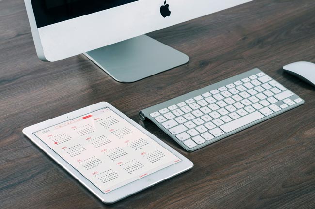iMac, iPad mit Apple-Tastatur auf einem Schreibtisch, Display ziegt Kalender. Bild: Unsplash/firmbee.com (https://unsplash.com/de/fotos/imac-aluminium-und-ipad-GANqCr1BRTU)