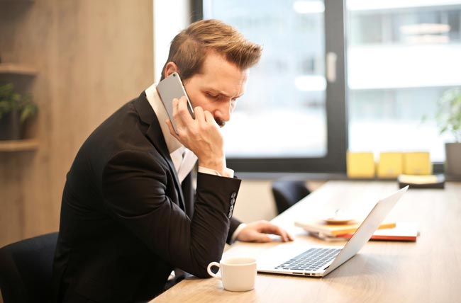 Vertrag kündigen: Mann am Laptop mit Handy in der Hand. Bild: Pexels/Andrea Piacquadio (https://www.pexels.com/de-de/foto/mann-der-einen-telefonanruf-vor-einem-laptop-hat-859264/)