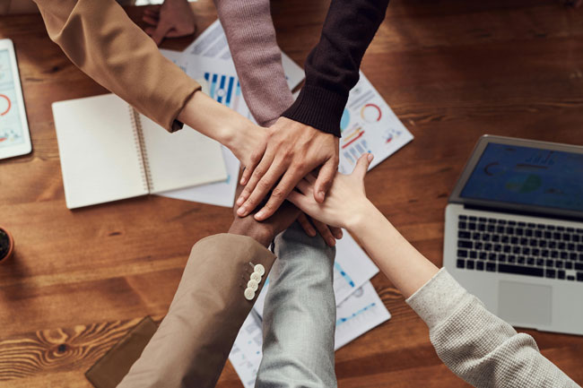 Change-Projekt | Mitarbeiter klatschen Hände aufeinander. Bild: Pexels/fauxels https://www.pexels.com/de-de/foto/foto-von-menschen-in-der-nahe-von-holztisch-3184418/