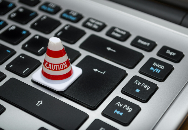 Captcha Hijacking I Ein kleiner Warnkegel steht auf der Tastatur. Bild: Pexels/ Fernando Acros