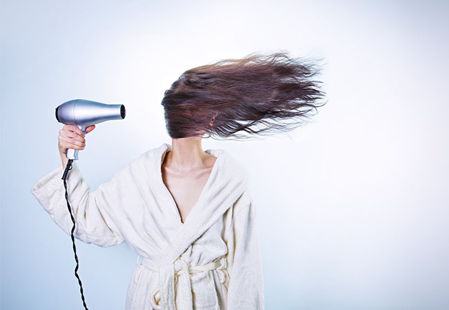 Frau mit Haarfön in Betrieb. Nur mit der richtigen Schutzklasse droht kein Stromschlag. Bild: Pixabay