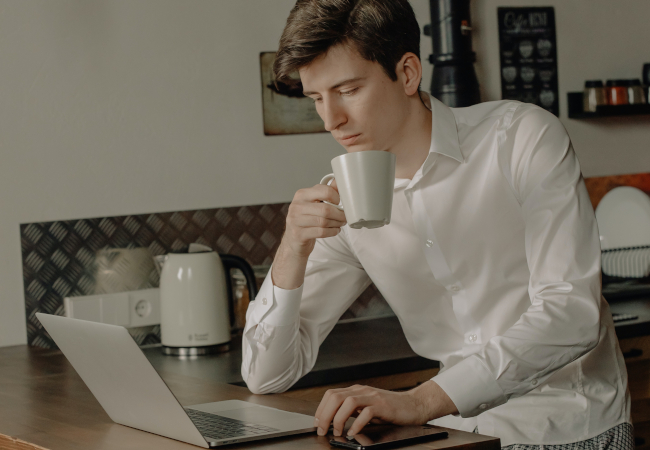 Ein Mann sitzt nachts in der Küche und stellt bei einer Tasse Kaffee sein Projekt fertig. Bild: Pexels/cottonbro