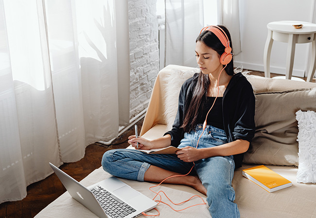 Internet-Geschwindigkeit: Junge Frau mit Laptop, Kopfhörern und Schreibblock. Bild: Pexels/Karolina Grabowska