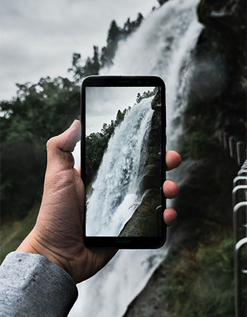 GIF selber machen: Hand hält Handy, Kamera nimmt Wasserfall auf. Bild: Unsplash/Julius Drost
