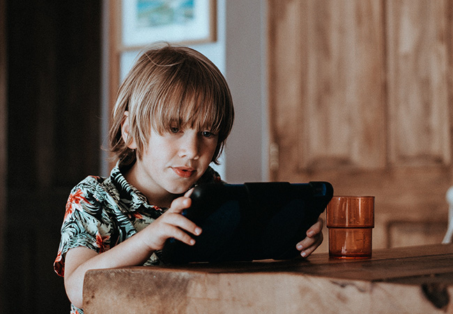 Das Bild zeigt einen Jungen, der sich mit einem Tablet beschäftigt. Mit dem Google-Konto für Kinder haben Eltern die Möglichkeit, die Internet-Nutzung Ihres Kindes einzuschränken und zu überwachen. Bild: Unsplash/Annie Spratt