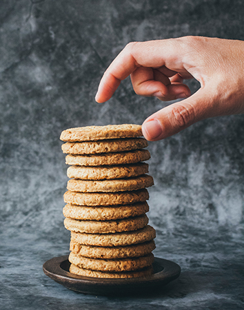 Cookies verwalten – ein Teller mit gestapelten Cookies, eine Hand nimmt einen Cookie weg. Bild: Unsplash/Tijana Drndarski
