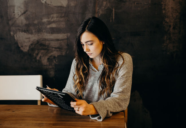 Das Bild zeigt eine Frau, die mit ihrem Tablet in einem Cafe sitzt und arbeitet. Bild: Pixabay