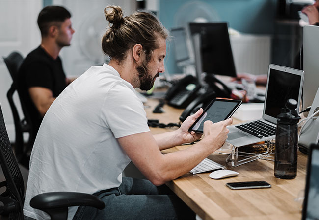 Das Bild zeigt einen Mann, der in einer öffentlichen Einrichtung mit seinem Tablet arbeitet. Foto: Pixabay