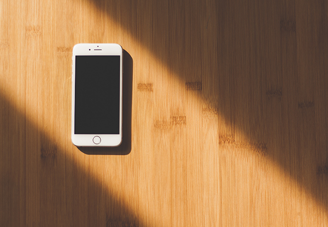 Weißes Smartphone auf einem Untergrund aus Holz mit Licht und Schatten – Smartphone-Sicherheit. Bild: Pexels/Negative Space